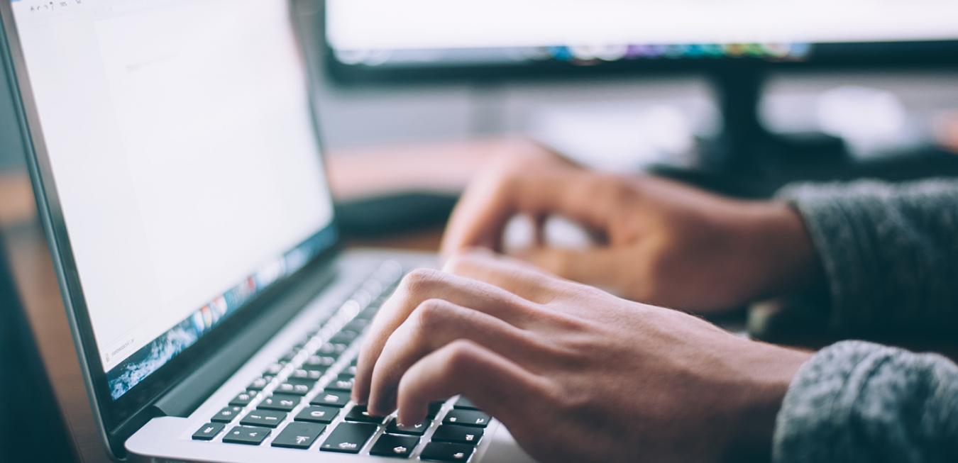 Image: Hands typing on a laptop keyboard.