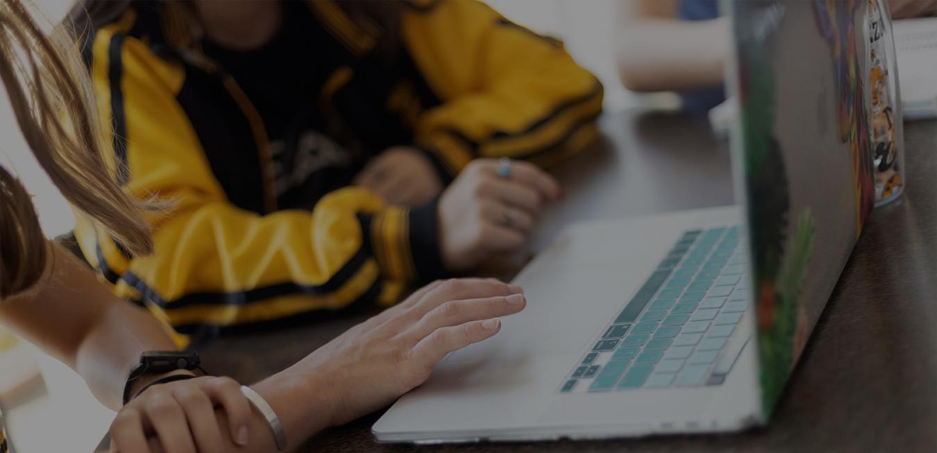 Students sitting and scrolling on a laptop